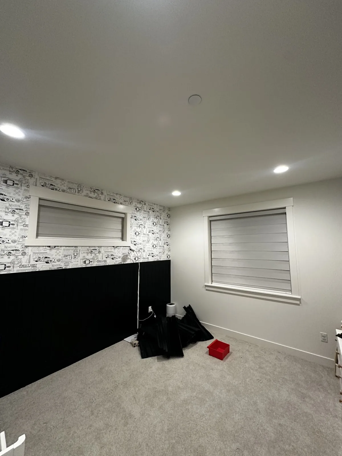 Gray zebra shades fitted to two windows in a room with car-pattern wallpaper