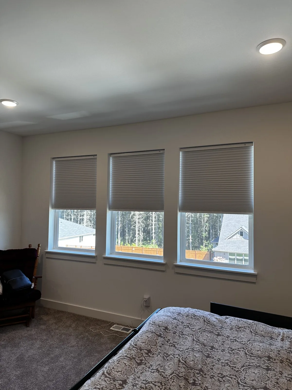 Three gray honeycomb shades partially lowered over bedroom windows