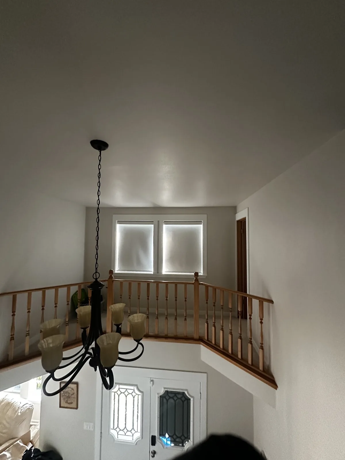 Two closed shades on upstairs landing windows above an entryway