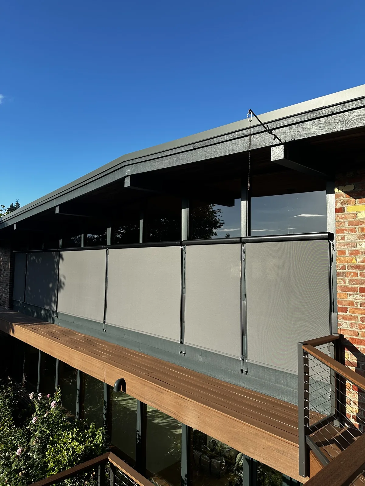 Gray exterior shades lowered across a row of windows above a wooden deck